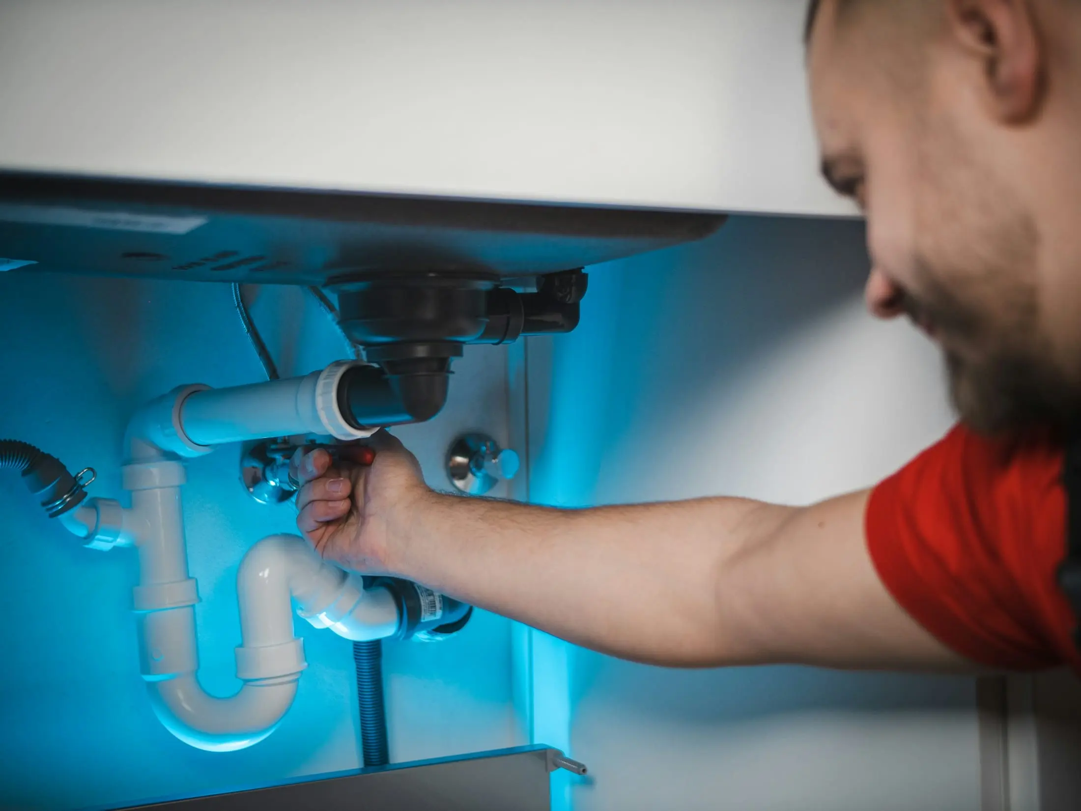 Installateur montiert einen Siphon unter einem Waschbecken